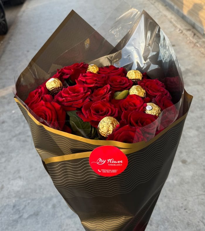 Un bouquet de fleurs rouges accompagné de chocolats Ferrero Rocher, créant une combinaison élégante et gourmande.